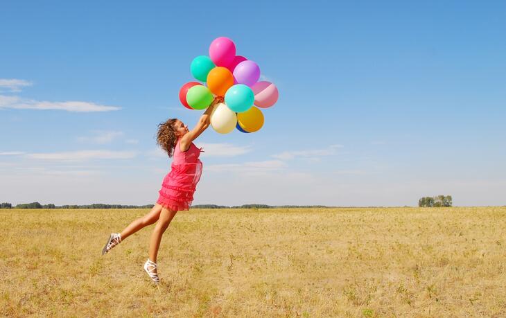 Bilde av jente som strekker seg etter ballonger