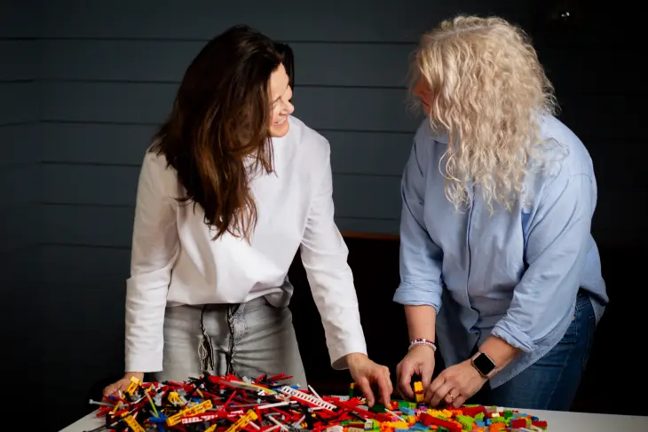 To damer som smiler og bygger lego i samarbeid